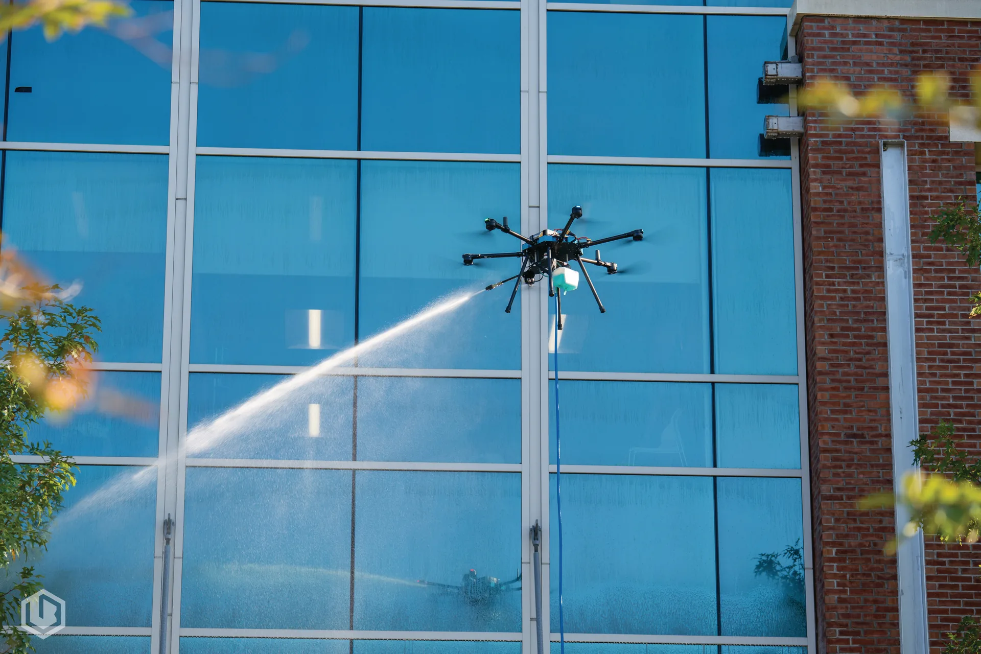 Drone pressure washing a building facade